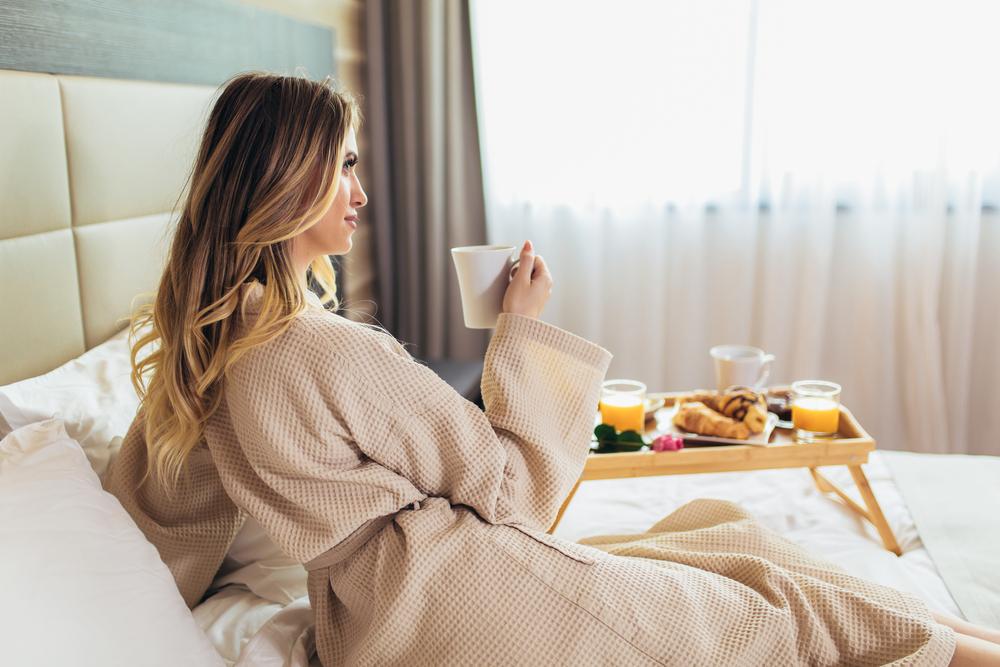 Hotel guestroom with a woman enjoying breakfast in bed